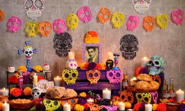 mexican day of the day offering with flowers, photographs, candels and the classic bread of dead.